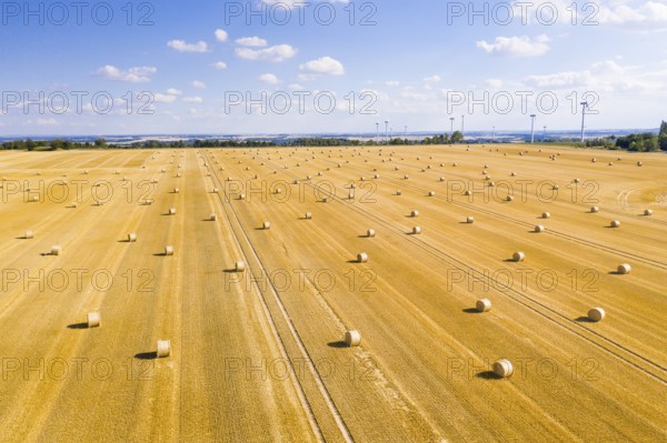 Straw bales on a harvested grain field from above, wind turbines in the background, Nossen, Saxony,