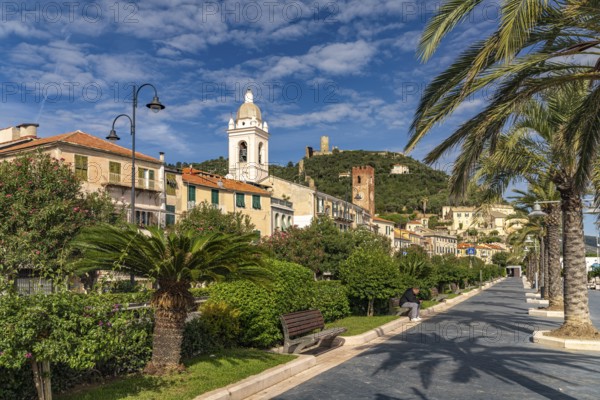 Palm trees on the promenade and cathedral of Noli, Riviera di Ponente, Liguria, Italy, Europe