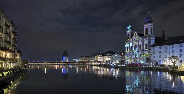 Water tower and Jesuit church on the right with light installation, on the Reuss at dusk, Old Town,