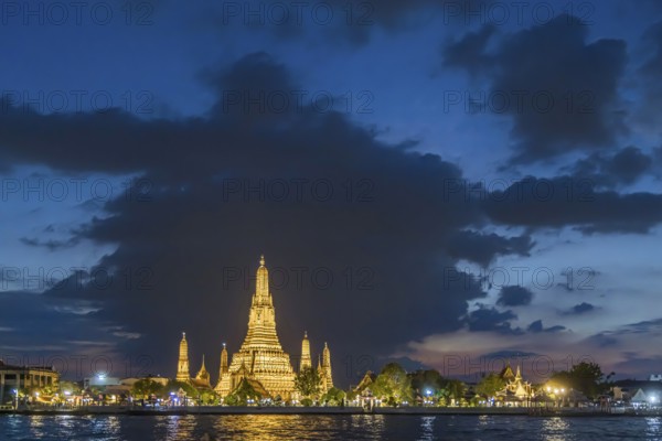 Wat Arun, Temple of Dawn at sunset with dark clouds. Boats on the Chao Phraya river. Tourist
