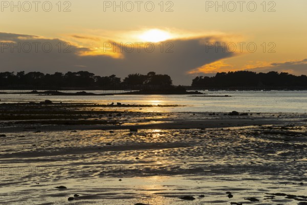 Sunset over the sea with golden reflections and coastal silhouette, Plage de Raluzet, Plougrescant,