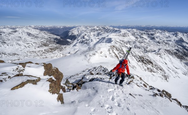 Ski tourers on foot, carrying skis on a rucksack, mountain panorama, snow-covered mountain