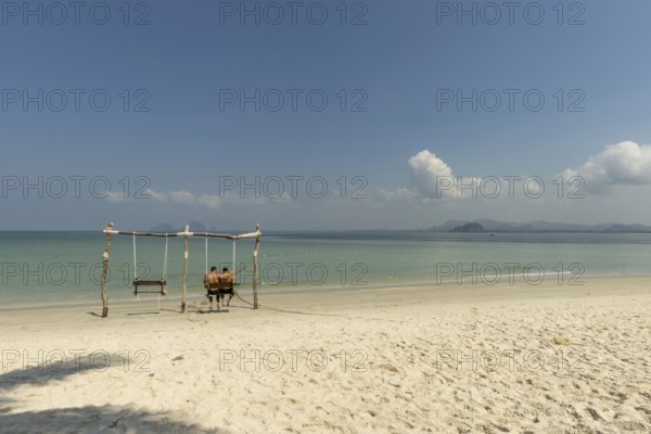 Gay couple in a swing on the beach of Koh Mook Island, Andaman Sea, Satun Province, Southern