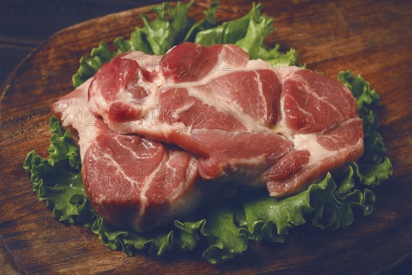 Raw pork steak, two pieces, on a wooden background