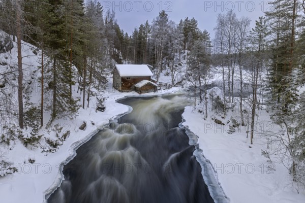 Old wooden Myllykoski water mill along the river Kitkajoki in winter, Oulanka National Park,