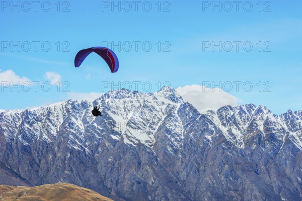 Paragliding over the snowcapped Remarkables mountain range, Queenstown, South Island, New Zealand,