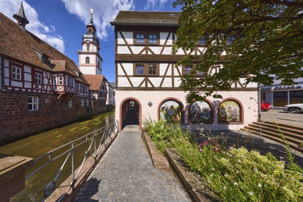 River Mümling, half-timbered houses, archway, church tower, metal railing, flower bed, blue sky