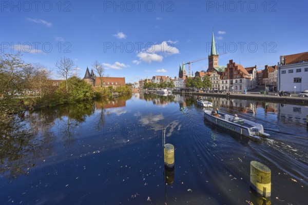 River Trave with quay wall, historic houses, Lübeck Holstentor, church towers of St. Marien and St.
