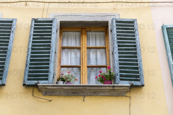 Wooden windows with flower pots and blue shutters in the medieval old town centre of Arezzo,