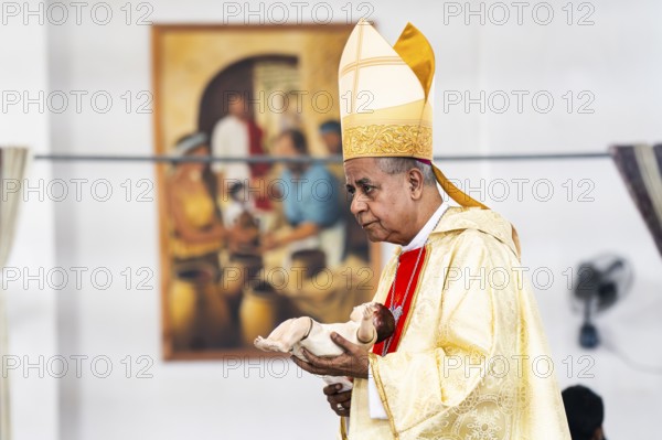 Archbishop John Moolachira holds an idol of baby Jesus Christ during a Christmas day sermon on