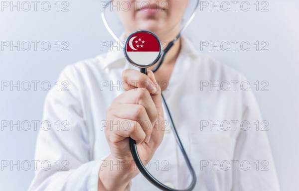 Doctor holding stethoscope with Singapore flag. National Health System of Singapore