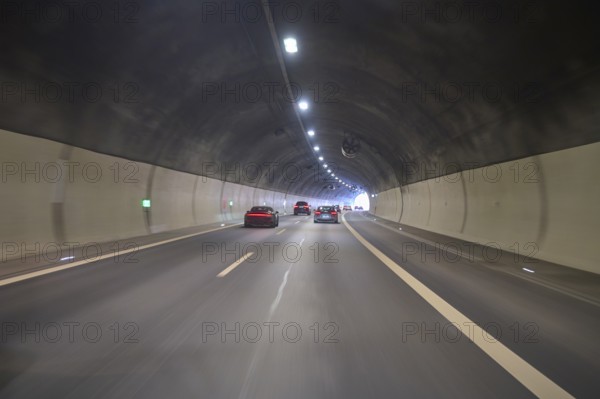 Motorway tunnel with several cars, illuminated by overhead lights, Switzerland, Europe