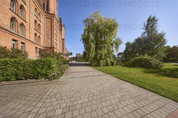 New town hall, brick building, architectural style neo-Gothic, former barracks, hedge, trees, lawn,