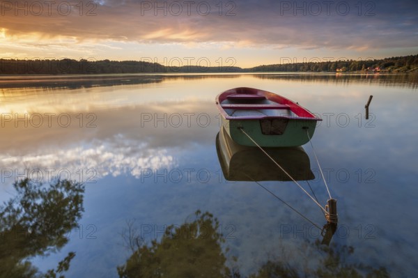 Quiet lake at sunrise, rowing boat moored in the water, Wutzsee, Lindow, Brandenburg, Germany,