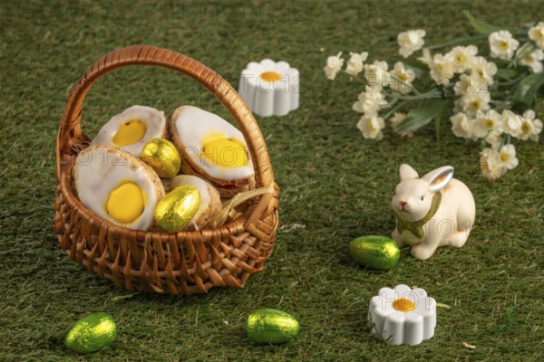 Easter biscuits in baskets with a bunny figure and flowers on a green lawn