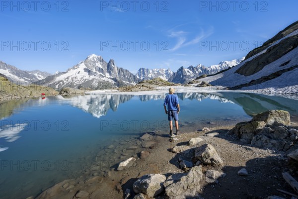 Mountaineer in front of mountain landscape with mountain lake, tourist at Lac Blanc with water