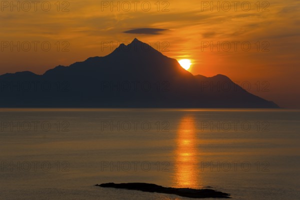 Dramatic sunrise over the mountains with golden reflections on the sea, majestic silhouette, view