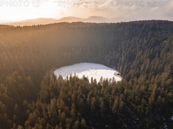 Aerial view of a circular lake in the midst of wintry fog and forest landscapes, Glaswaldsee, Bad