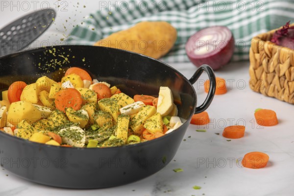Parsley falls onto chopped vegetables and potatoes in a saucepan, surrounded by fresh ingredients