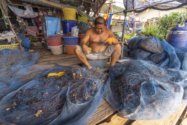 Fisherman repairing his net, fishing village Ban Ao Salad, island Ko Kut or Koh Kood in the Gulf of