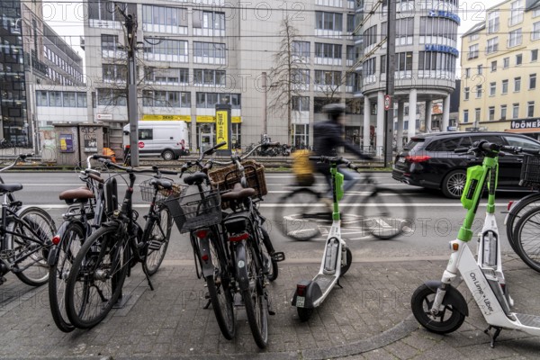 Cycling in the city centre, here at Neumarkt in Cologne, parked bikes and e-scooters at the