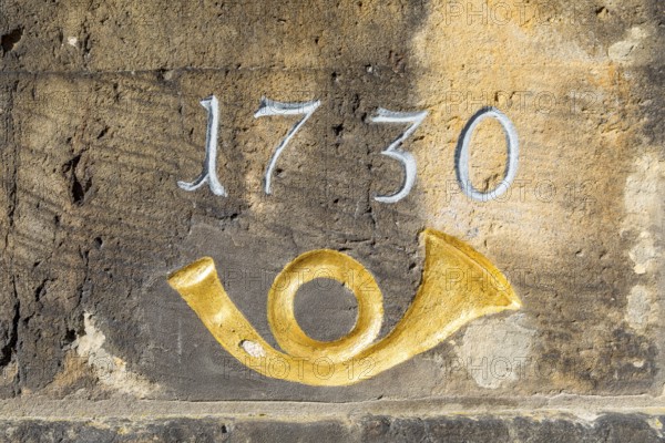 Year 1730 and post horn in gold, detail on the historic post milestone column near the castle in