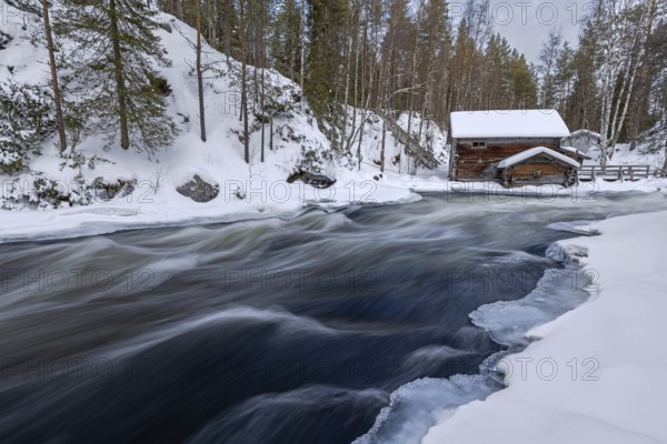 Old wooden Myllykoski water mill along the river Kitkajoki in winter, Oulanka National Park,