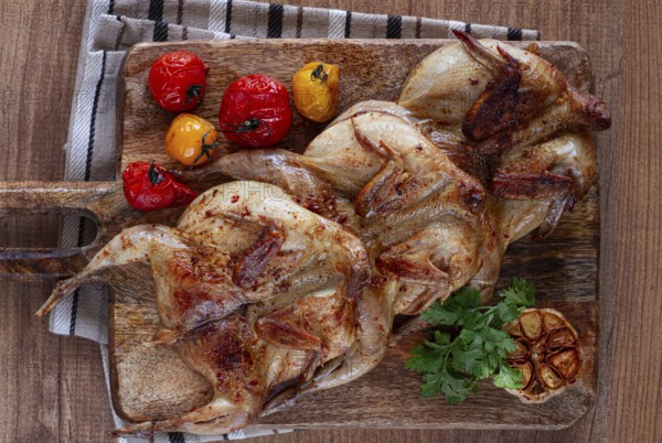 Grilled quail meat, on a wooden chopping board, tobacco, in the oven, with spices, homemade,