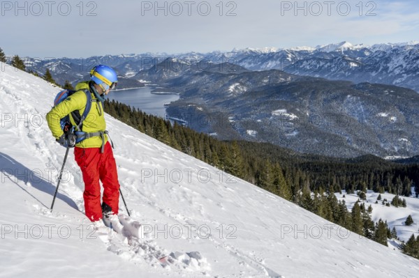 Skiers skiing down the Simetsberg, view of Walchensee and mountain panorama, Estergebirge, Bavarian