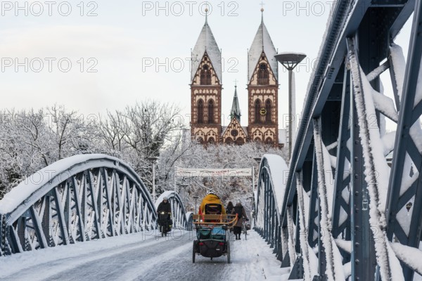 Bridge with snow and ice and cyclists, Blue Bridge and Stühlinger Church, Freiburg im Breisgau,