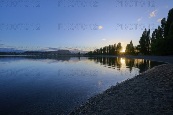 Calm lake at sunrise with clear reflection of the trees and slightly cloudy sky, summer, Lake