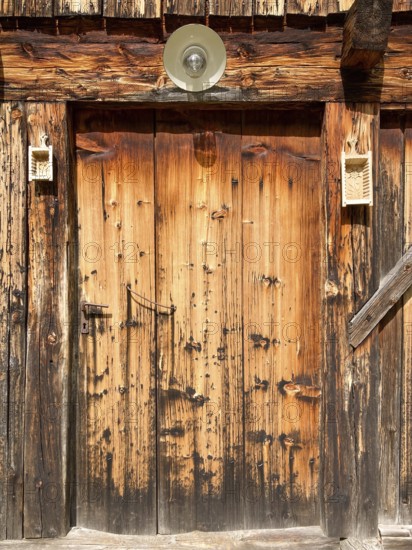 Entrance door of a rustic old weathered alpine hut decorated with butter moulds, East Tyrol,