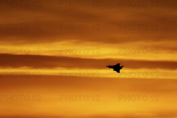 Eurofighter Typhoon silhouette of aircraft in RAF Royal air force colours flying at sunset,