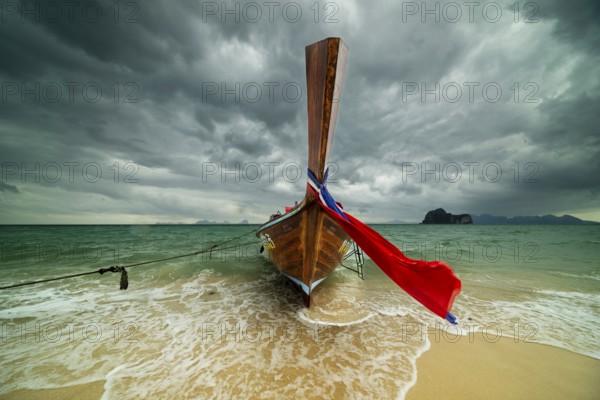 Longtail boat on the beach, dark rain clouds behind, Koh Ngai Island, Andaman Sea, Satun Province,