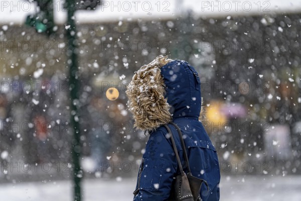 Winter weather, heavy snowfall, city centre traffic, passers-by in the snow, person with fur hood