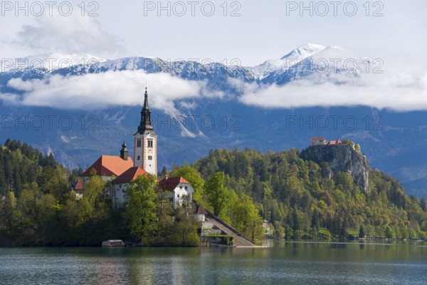 Church on a wooded island in a lake, with mountains in the background, Bled Island with St Mary's