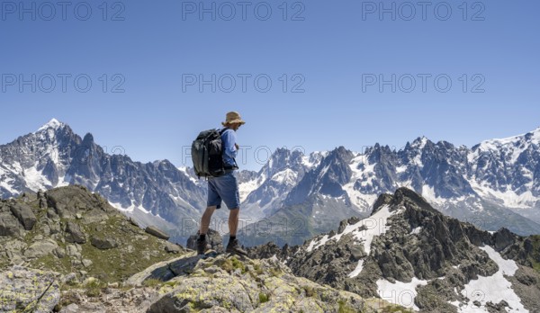Mountaineer on a rock, mountain landscape with mountain peaks Aiguille Verte and Grandes Jorasses,