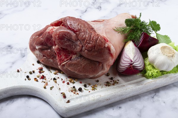 Raw pork knuckle, on a wooden chopping board, with spices, close-up, top view, no people
