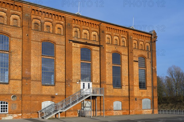 Brick building with large windows and metal staircase in front of a clear blue sky, blower hall,