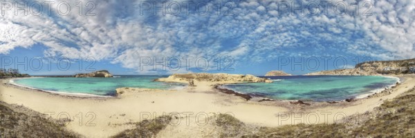 Wide panorama of Frangolimiona sandy beach with turquoise sea and slightly cloudy sky, Arkasa,