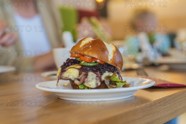 A juicy burger with vegetables served on a pretzel bun in the restaurant, autumn creations, Cafe