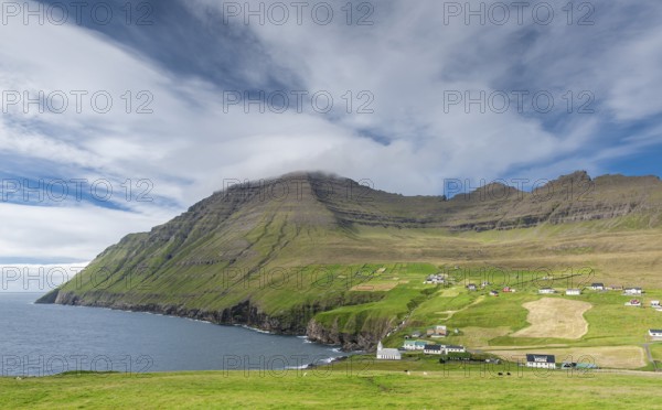 Coastal landscape with mountains and village under blue sky, Vidareidi, Vidoy Island, Viðareiði,