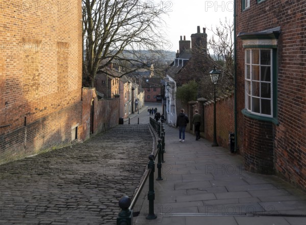 People walking on Steep Hill in evening light, Lincoln, Lincolnshire, England, UK
