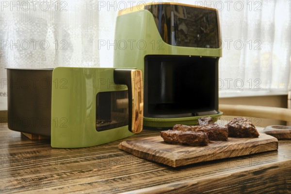 A stylish kitchen corner showcases an air fryer beside a cooking unit. Juicy pieces of grilled meat