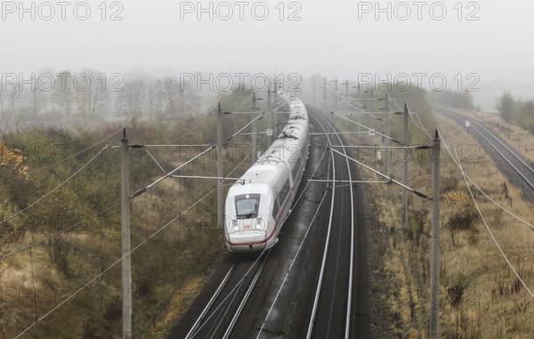 A Deutsche Bahn ICE train runs in foggy autumn weather on a railway line near Neugarten, 06.11
