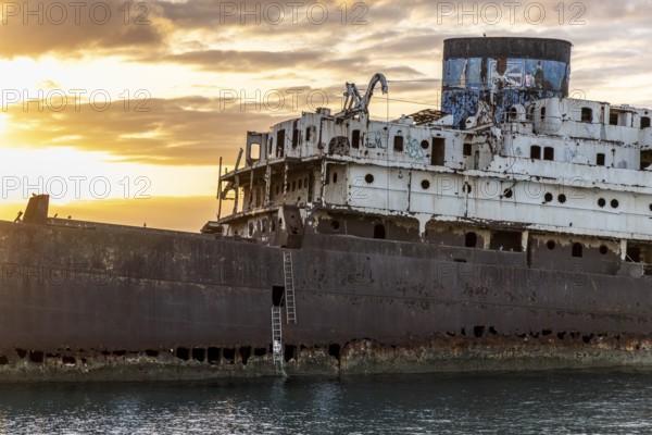 Lost place, ghost ship, close-up of an old, rusty shipwreck surrounded by water, illuminated by
