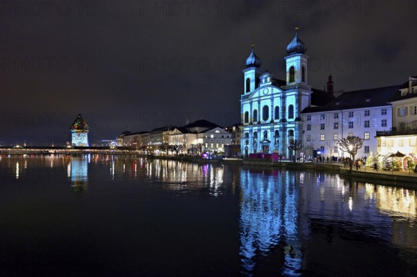 Water tower and Jesuit church on the right with light installation, on the Reuss at dusk, Old Town,