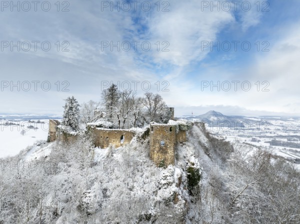 Aerial view of the snow-covered Hegau volcano Mägdeberg with remains of a castle wall on a cold