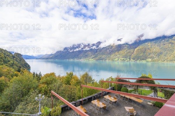 View of a lake with surrounding mountains and a terrace with tables, Lake Brienz, Switzerland,
