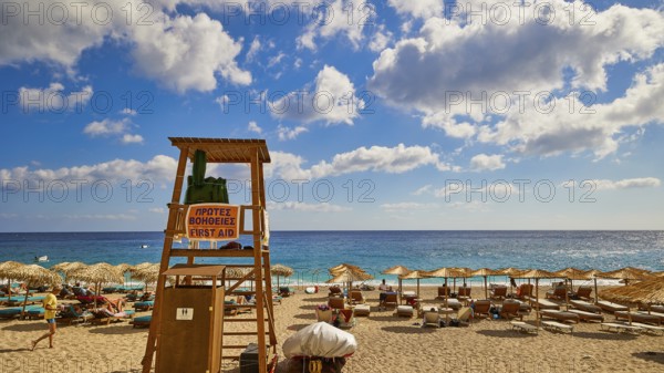 A lifeguard tower on the beach surrounded by parasols and sunbeds, with a sweeping view of the sea